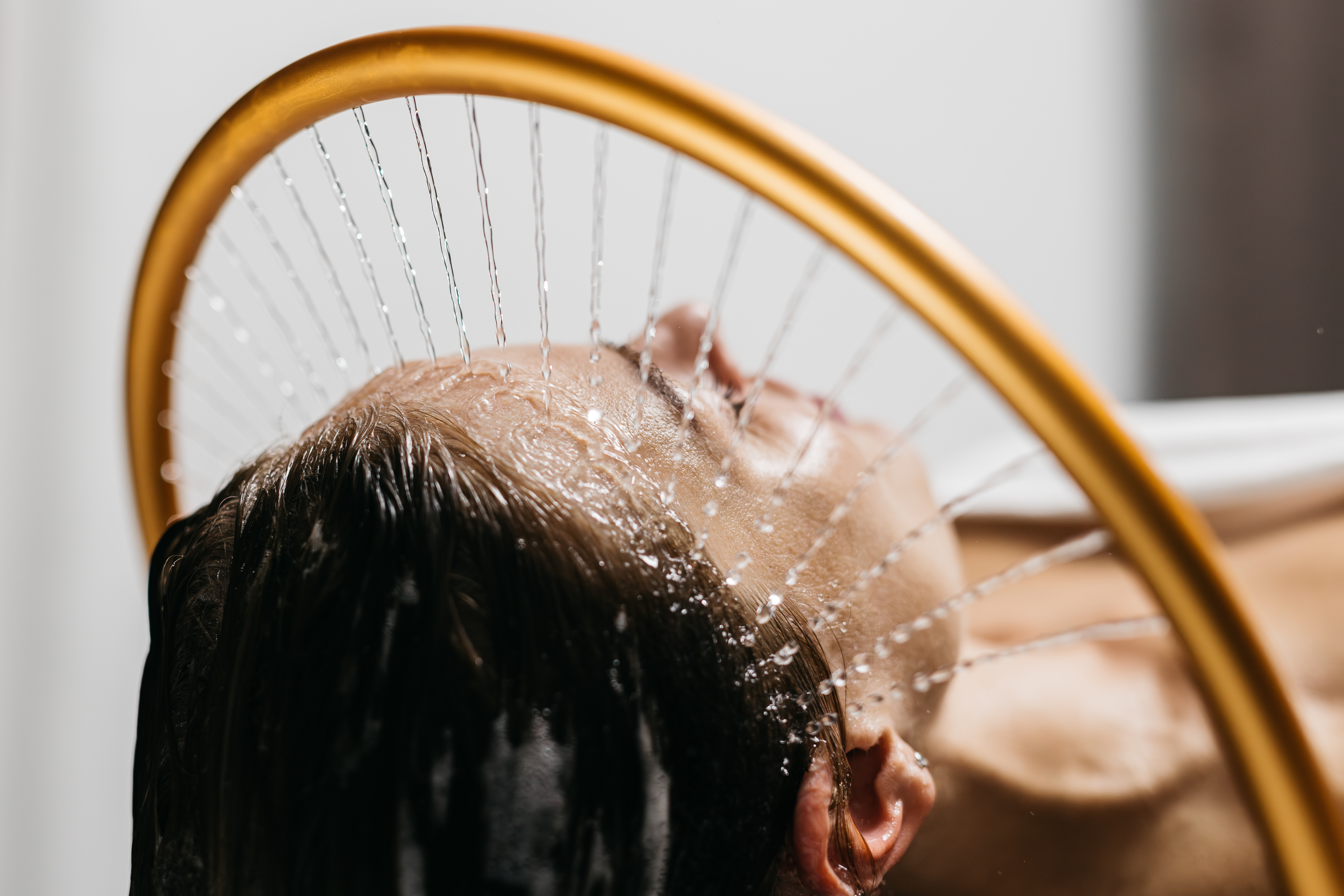 Woman with water gently streaming over her hair in a spa.